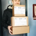 Kurir tersenyum memegang paket pengiriman siap diantar ke alamat tujuan